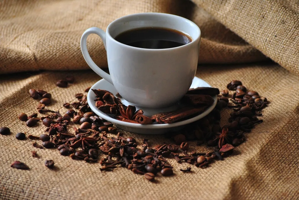 Xícara de café sobre tecido de juta com grãos ao redor