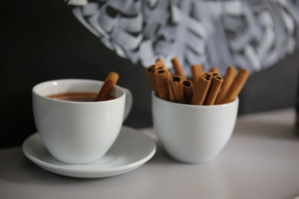 Pau de canela ao lado de uma xícara de café