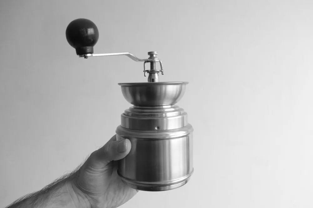 Moedor manual de café sendo girado à mão