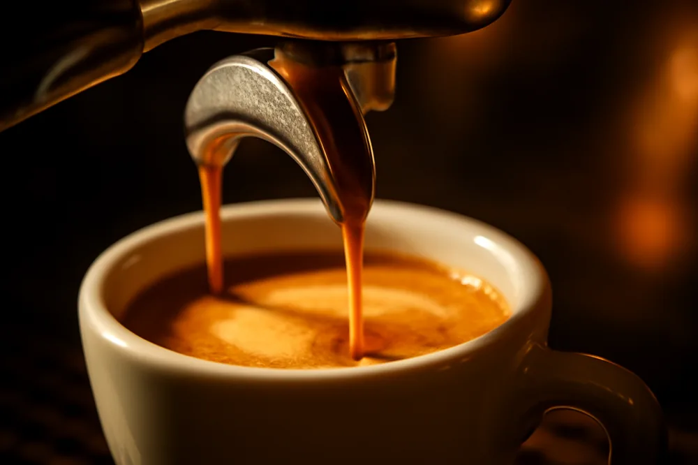 Espresso sendo extraído com crema dourada numa xícara pequena