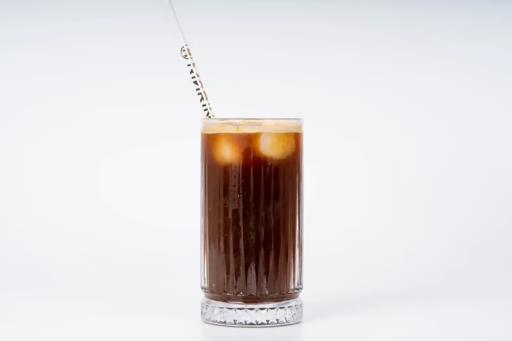 Copo de café gelado escuro com espuma cremosa
