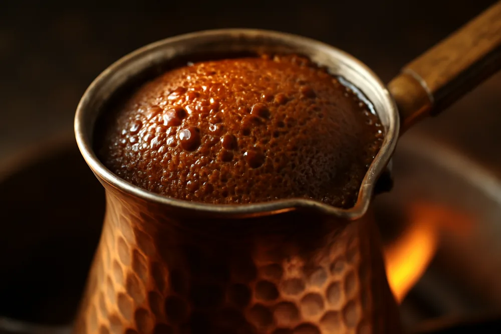 Café turco fervendo num cezve de cobre com espuma subindo